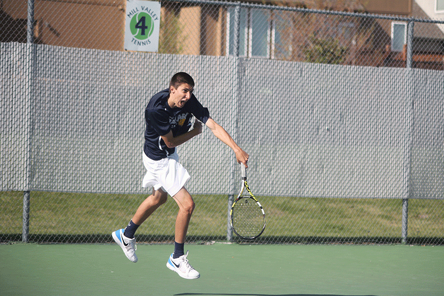 Junior Andrew Bock jumps as he serves the ball during a doubles match. 