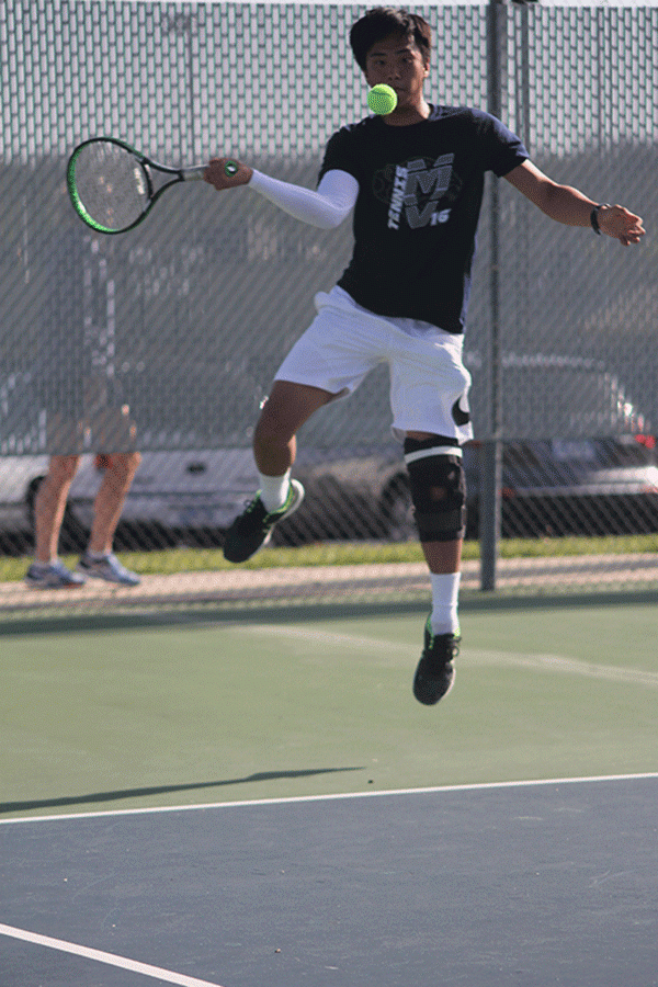Junior Parker Billings jumps to swing at the ball during a singles match.