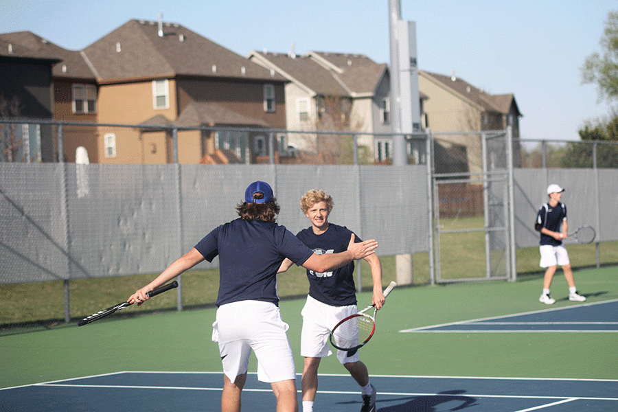 Sophomore Dante Peterson high fives doubles partner senior Tyler Shurley after winning their match against St. James. 