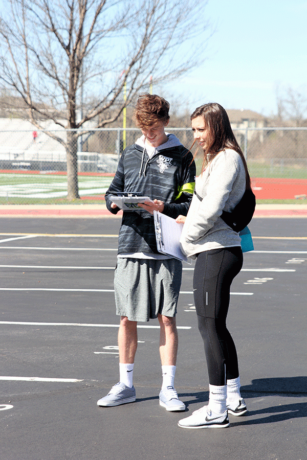 Junior Jakob Coacher and senior Katie Burke volunteer at Drive 4 UR School, helping test drivers get to the correct car and holding paperwork.