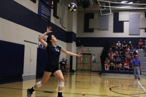 Throwing the ball upward, sophomore Grace Lovett serves.