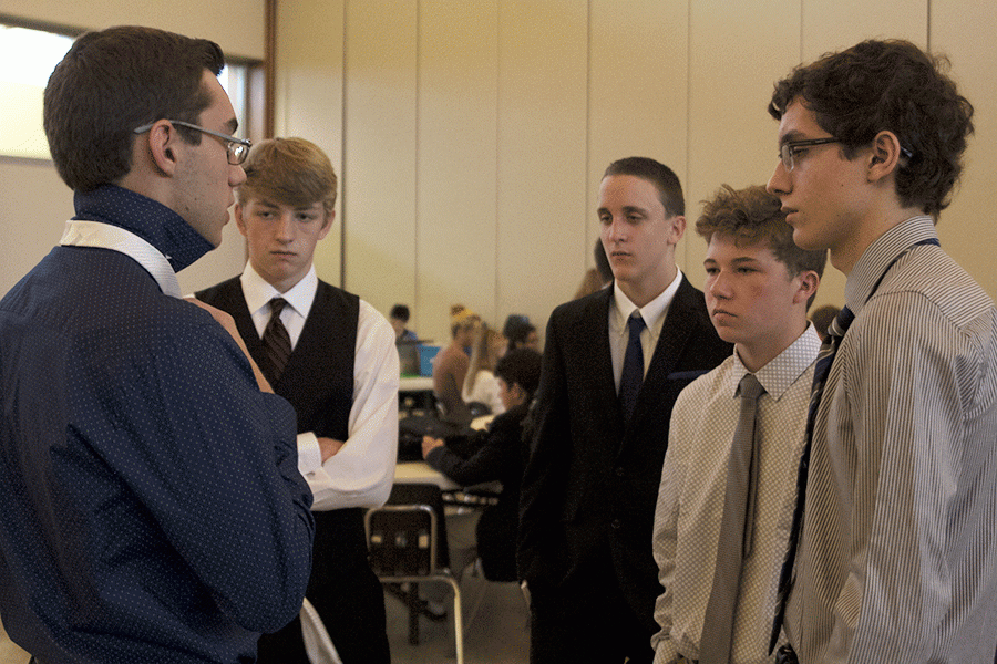 Senior Tom McClain shares tips with other debate members as they prepare for their first round of their debate meet on Saturday, Sept. 17 at St. James Academy. 