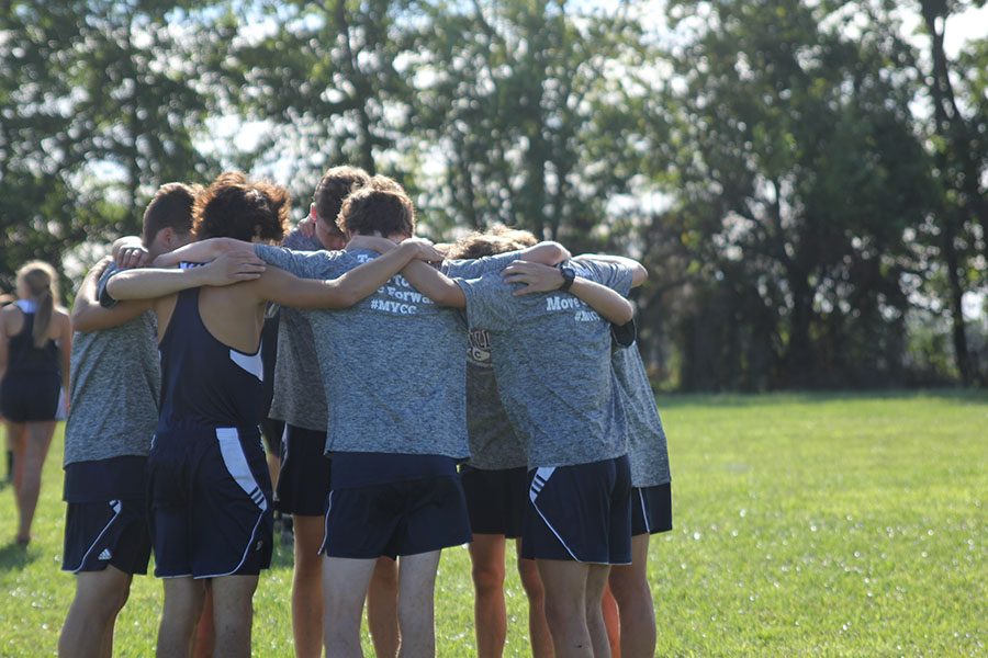 The boys varsity cross country team huddles before the start of their 5000 meter race.