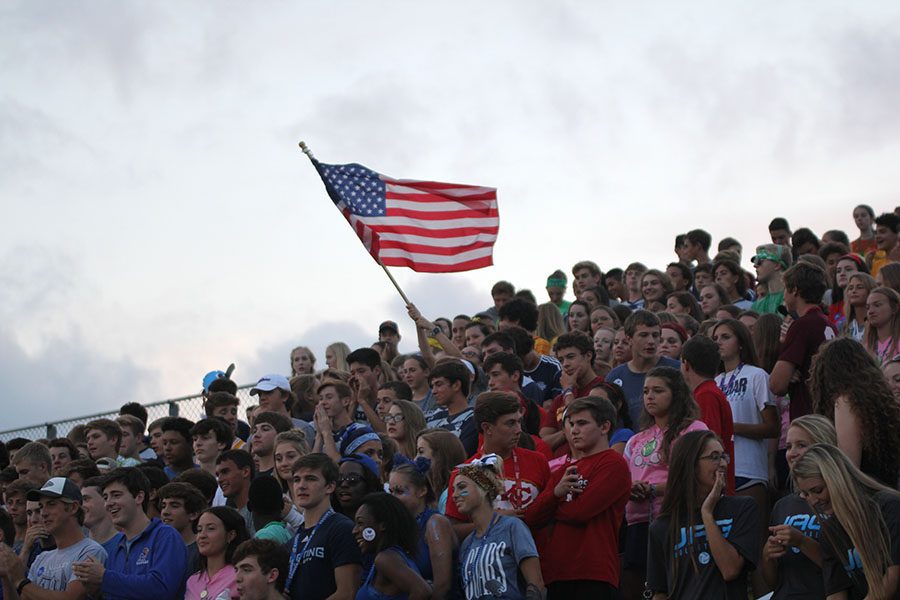 Sophomore Delaney Kemp holds a american flag in the student section.