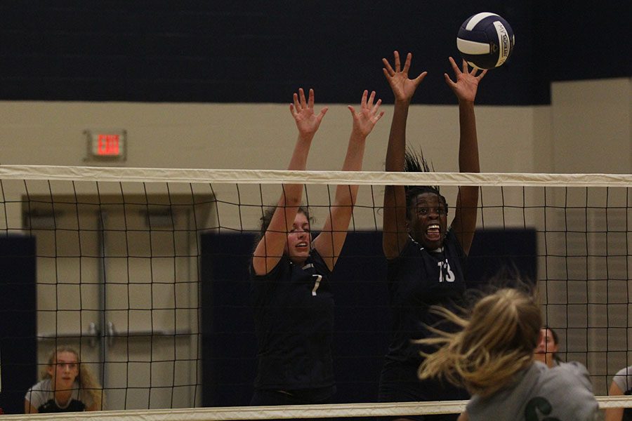 Hands raised, senior Maggie Bogart and junior Abigail Archibong jump to block Blue Valley Southwests ball during a triangular match on Tues., September 7.