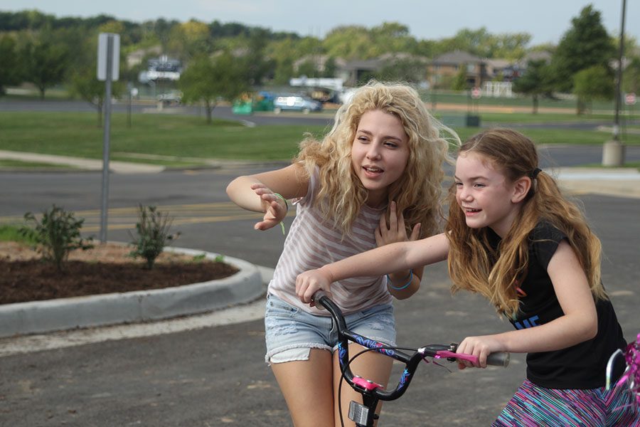 Leading the Whipping Childhood Cancer Triathlon on Saturday, Sept. 24, senior Emma Wilhoit directs a participant towards the beginning of the course. The course included biking, running and a pie in the face and children fifth grade and under were able to participate. 