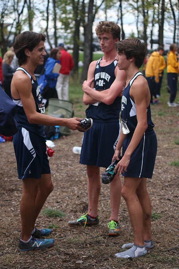 With his shoes off, sophomore Greg Haynes meets with senior Jakob Coacher and junior Gavin Overbeck after the race.