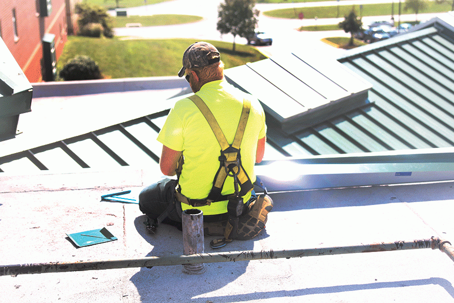 While sitting on the roof, a Quality Roofing worker replaces the lining above the B-hallway on Monday, Oct. 3.