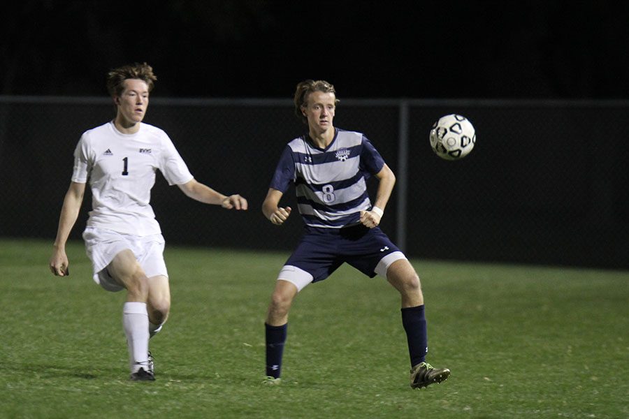 Defending the ball, senior Spencer Butterfield blocks a Blue Valley West player.