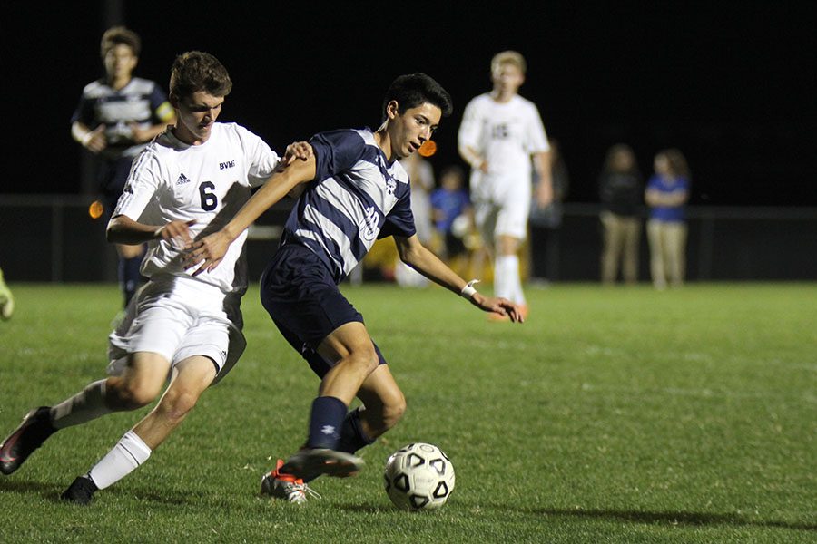 Protecting the ball, junior Drake Brizendine blocks a Blue Valley West player on Tuesday, Oct. 18. The Jaguars beat the Tigers 2-1.