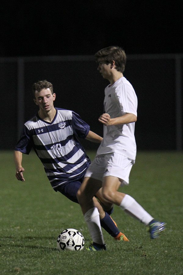 Losing possession of the ball, senior Ethan Doyle races in front of a Blue Valley West player.