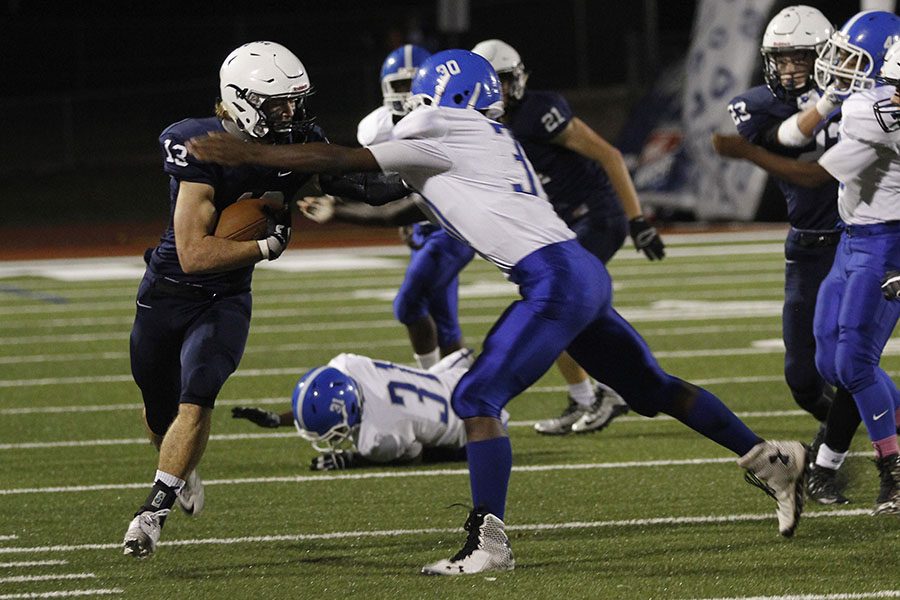 Avoiding a tackle, senior defensive back Joel Donn runs with the ball.