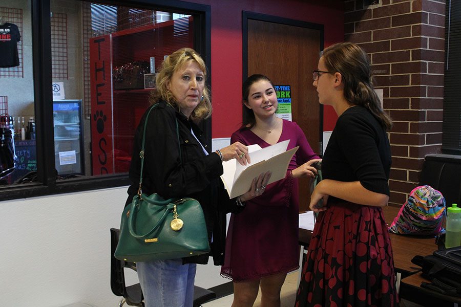 Two debate team members converse with their sponsor, Jeanette Hardesty.