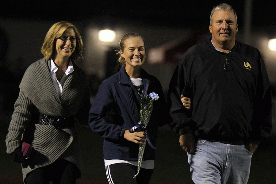 Linking arms with her parents, senior Meg Green is recognized for girls golf on Friday, Oct. 21 for senior night.