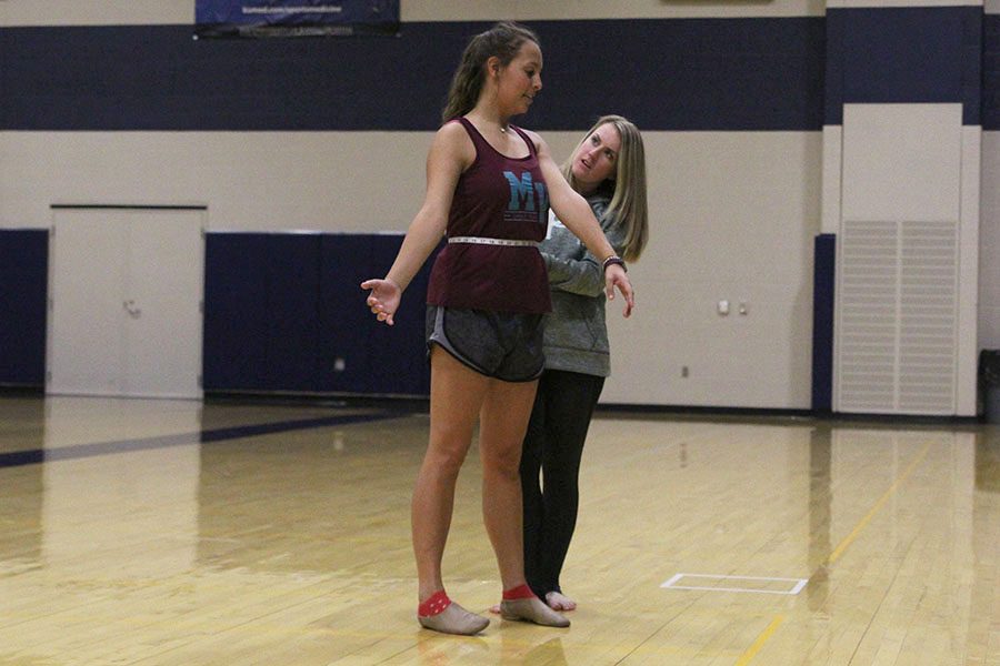 Tape in hand, assistant dance coach McAfee measures senior Lauren Schath for competition outfits at practice on Tuesday, Oct. 18.