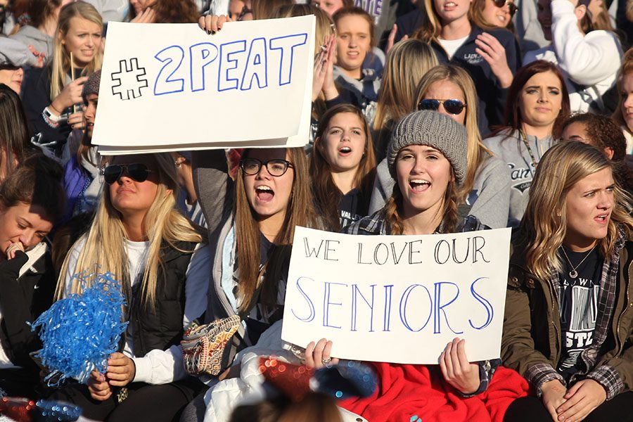 Seniors Paige Lewis and Claire Rachwal hold up signs in the student section.