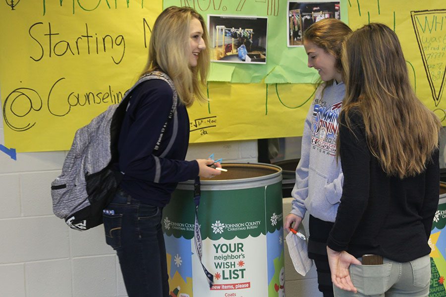 Junior Madison VanBuler puts coat in the bins in the foyer Tuesday, Nov. 8 for the NHS coat drive. 