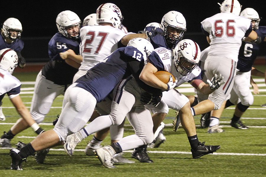 Pushing him over, senior line backer Brady Garrison tackles the St. James player.