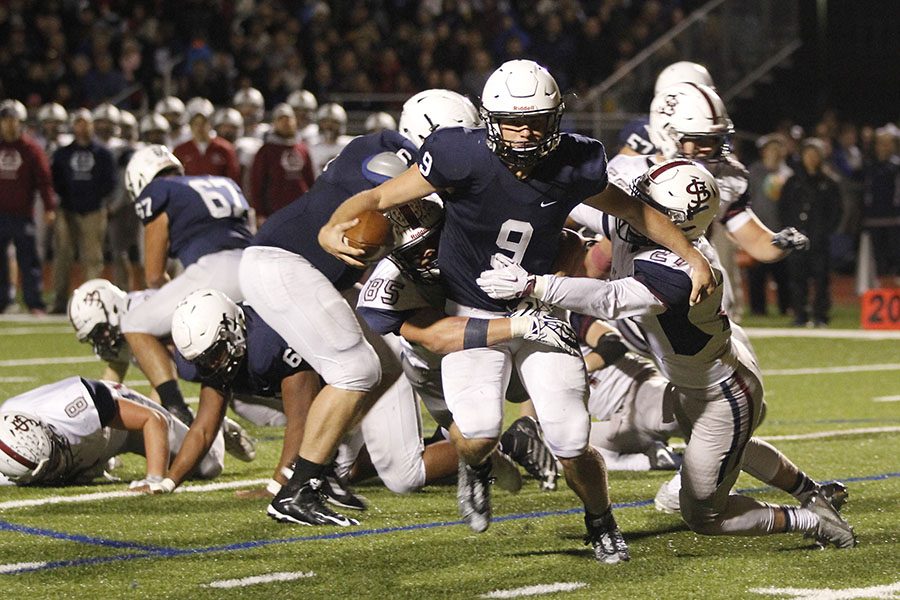 Pushing through the block of St. James players, junior quarter back Brody Flaming attempts to avoid the tackle.