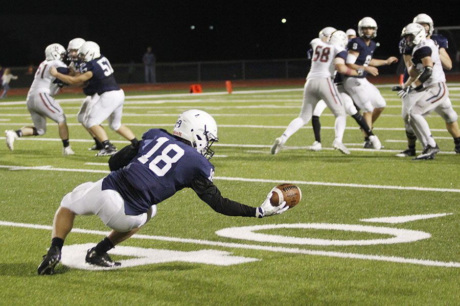 Reaching out, junior wide receiver Evan Rice attempts to catch the ball with one hand.