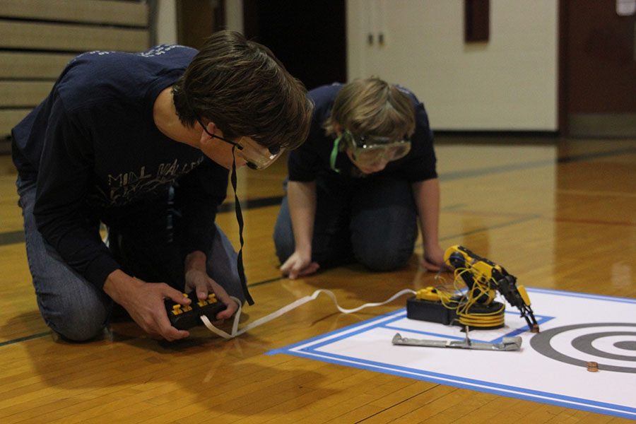 Sophomores Adam Bachoroski and Andrew Thomas try to push as many pennies into the center circle with their robot arm.