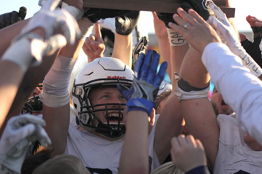 Senior Cole Ivey looks up at the state championship trophy as he holds it.