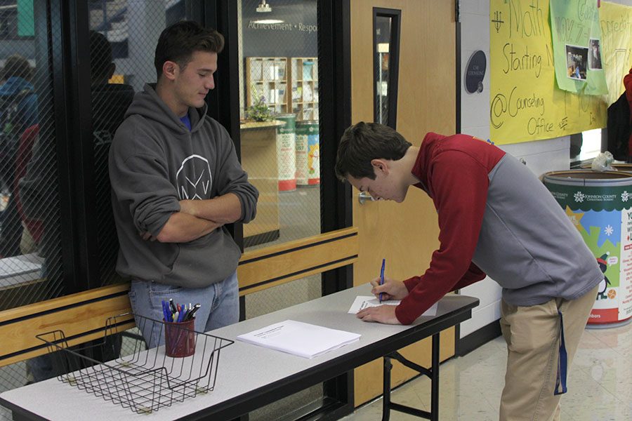 Before heading to class, senior Adam Gillette fills out one of the new department of the month forms on Wednesday, Nov. 9. 