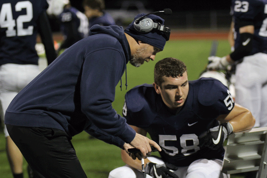 During the football game against St. James on Friday, Nov. 11, football and track coach Eric Thomas reviews a play with sophomore Christian Roth. 