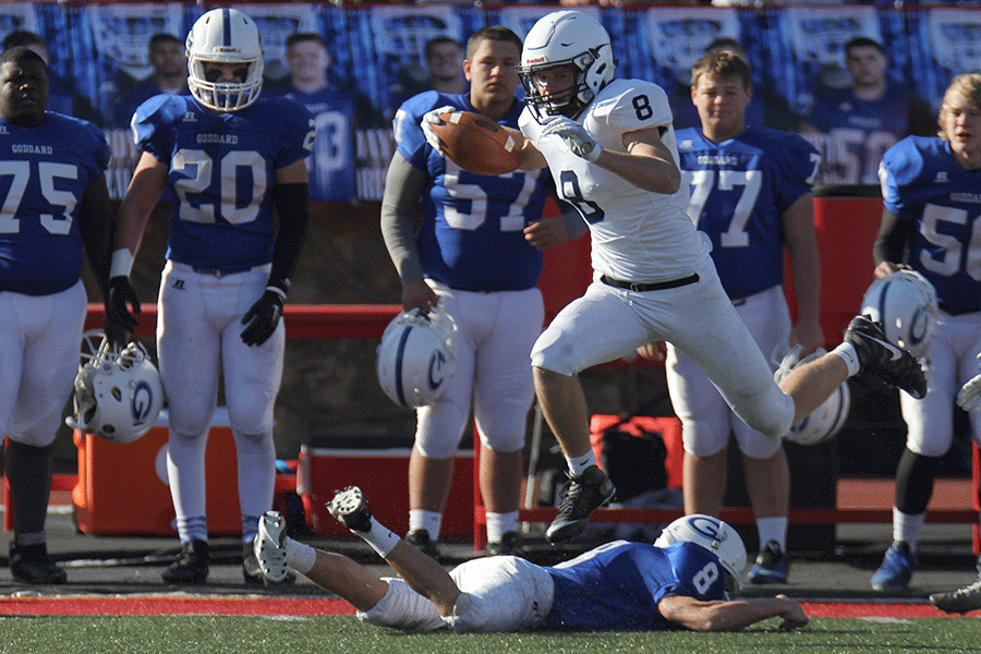 Jumping over his opponent, senior Ben Hartman runs the ball down the field for a kickoff return on Saturday, Nov. 26 at the 5a state championship game.