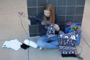 Working on a dinosaur-themed hat she designed herself, junior Marissa Olin is able to knit anywhere, as long as she has her materials.