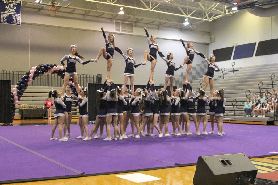 The cheer team completes a large stunt using all of the cheerleaders on the team.