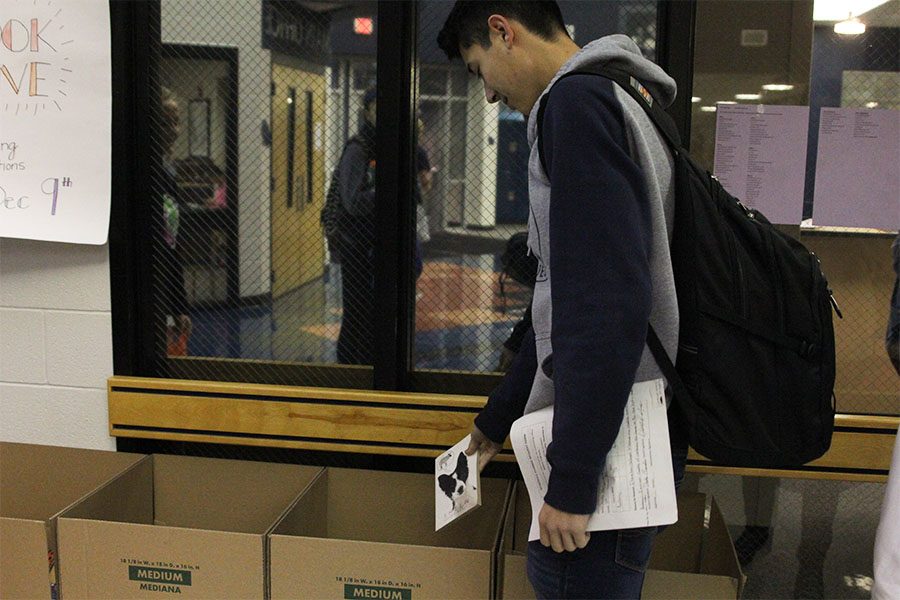 Junior Drake Brizendine places his book in the box for donation.
