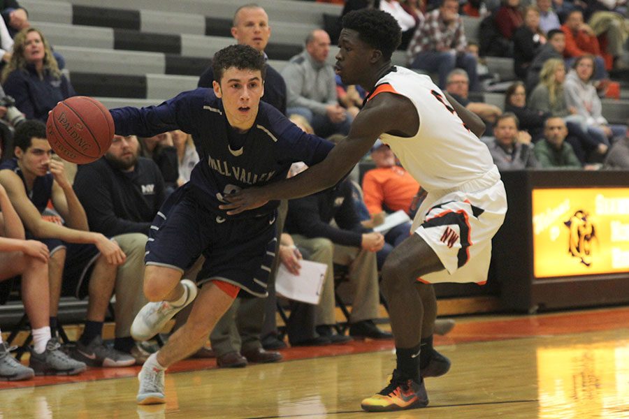 Running past a defender, senior Blake Montgomery dribbles toward the basket. The Jaguars were defeated by the Shawnee Mission Northwest Cougars 51-44 on Tuesday, Dec. 6. 