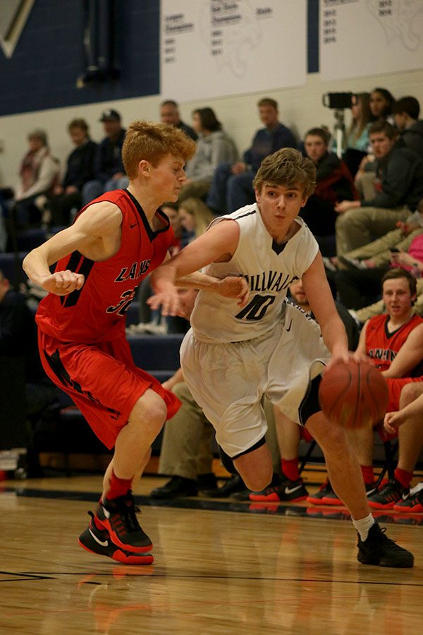 Shielding the ball from his opponent, senior Jack Cooper dribbles towards the basket.