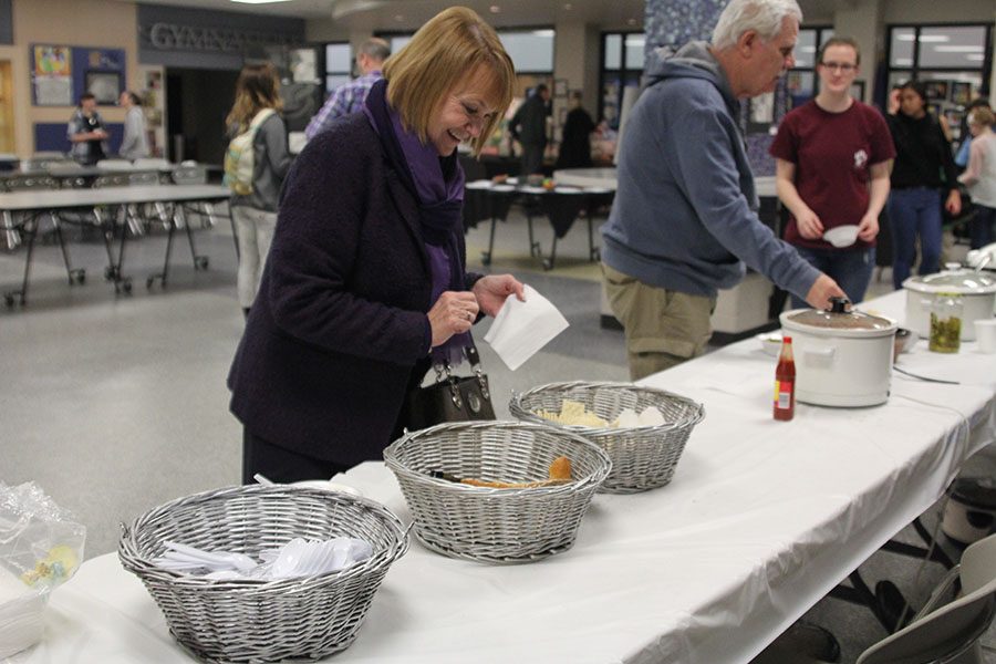 While smiling, a family member of a Mill Valley student grabs a bowl of chili.