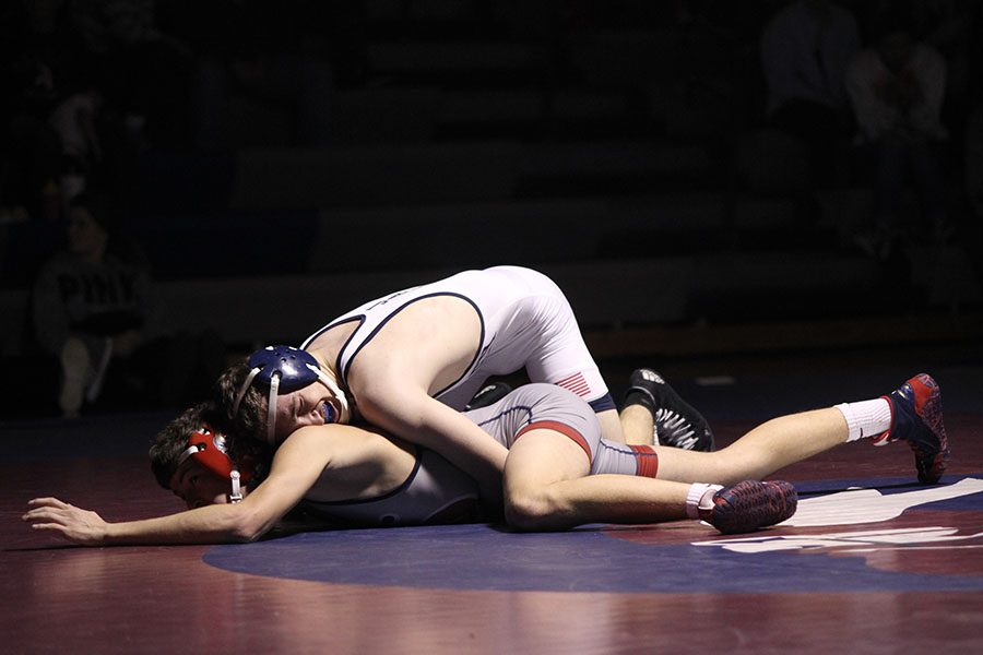 Holding his opponent down, junior Devon Handy struggles to win his match.