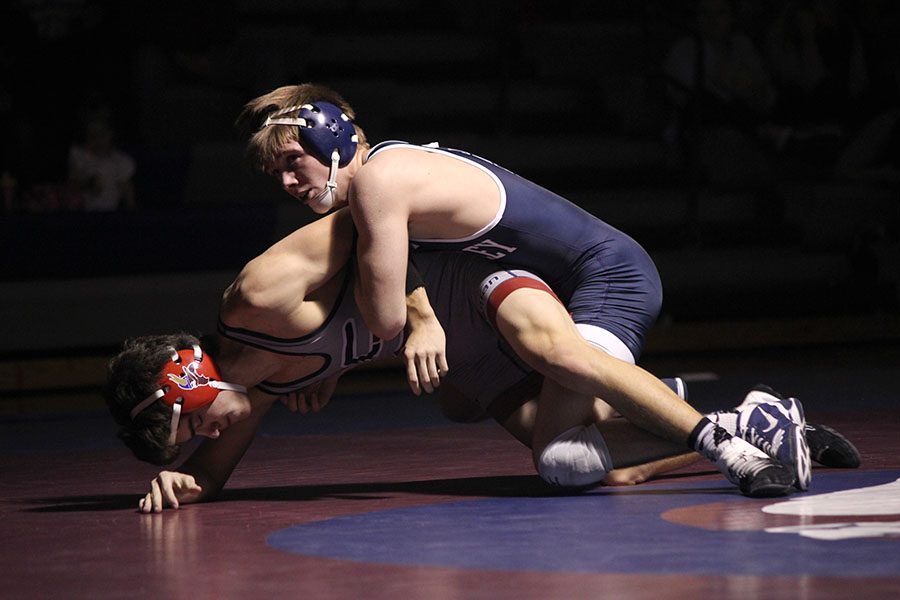 Holding his opponent down, junior Jarrett Bendure checks the score during his match.