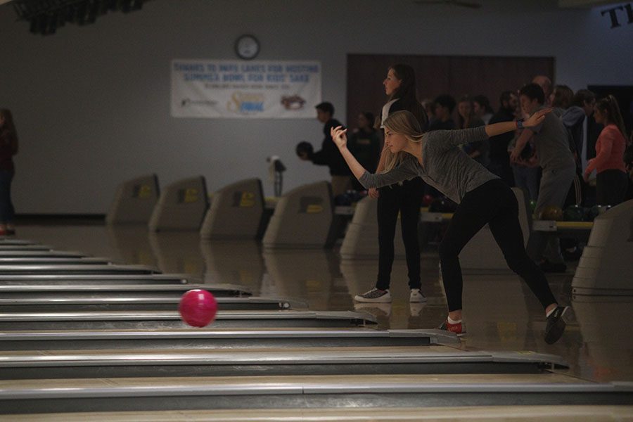 Focusing on her bowling form, junior Bella Hadden, watches the ball roll down the lane.