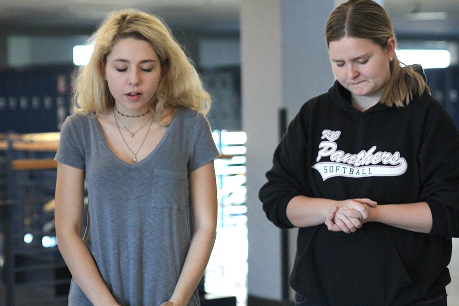 Standing in the freshman locker bank, senior Emma Wilhoit prays aloud alongside junior Grace Abram. The prayer walk, held on Tuesday, Feb. 21, allowed students to come together to pray for issues seen at school. 