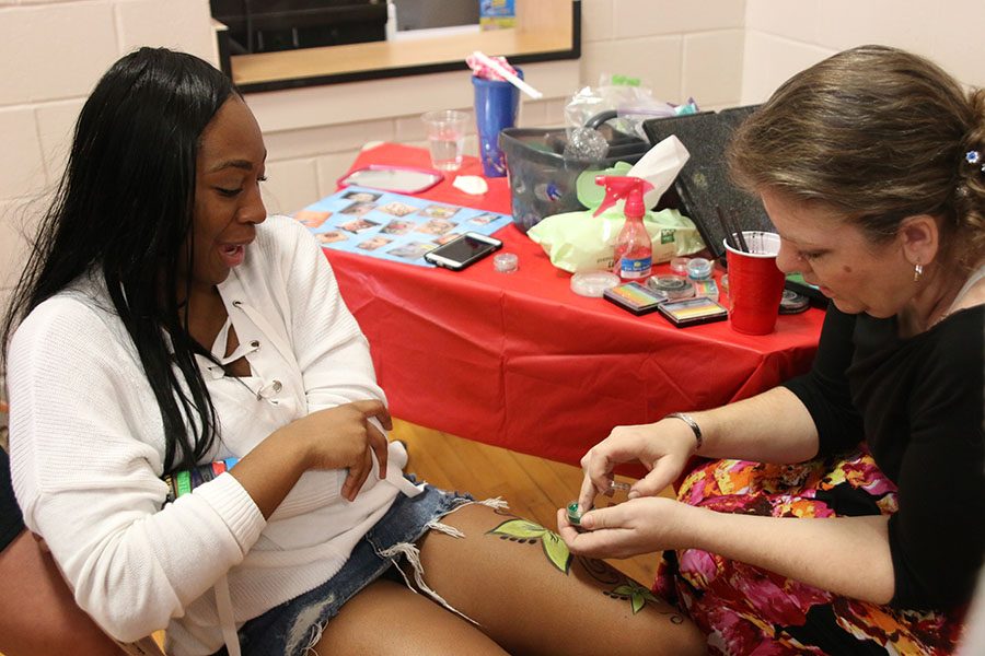 Senior Jasmine Cousins gets a flower painted on her leg.