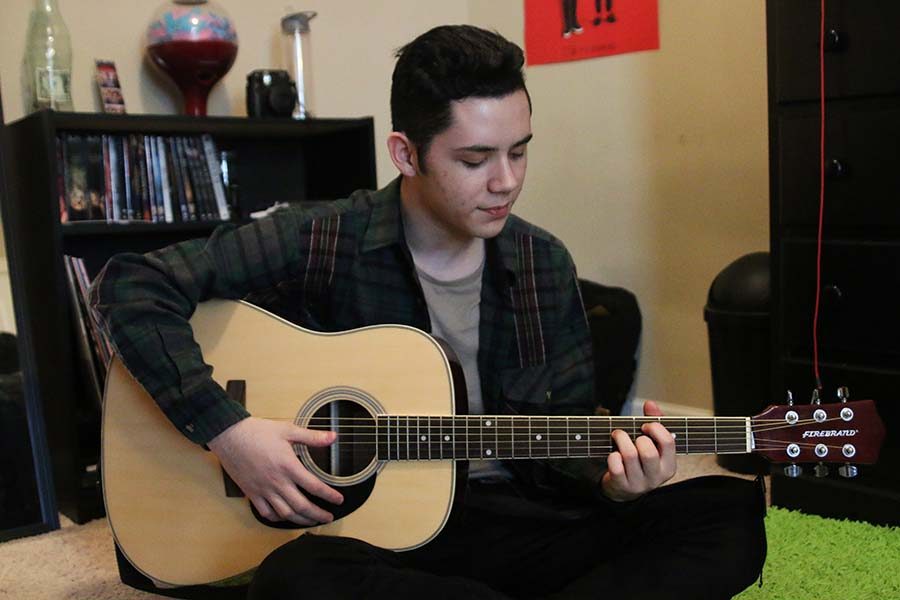 Looking down at the fret board on Monday, February 27, sophomore Dominic Martinez plays a variety of chords while strumming with his right hand.