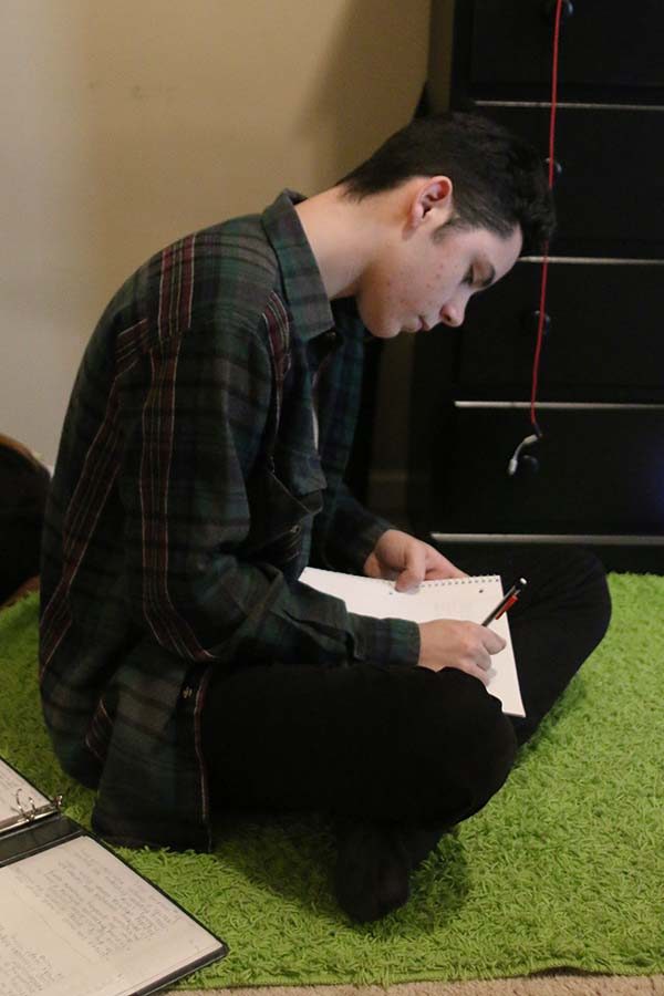 Sitting on the floor of his bedroom, sophomore Dominic Martinez writes down song ideas and lyrics in his notebook.