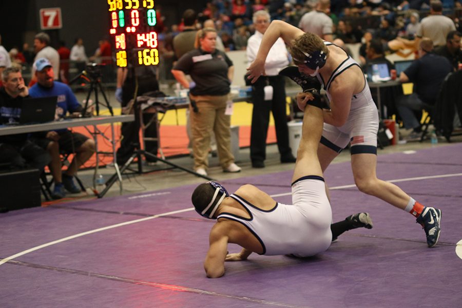 Senior Jett Bendure holds his opponents leg during his match. 