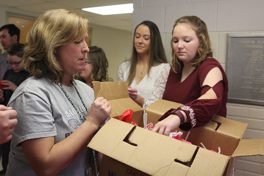 Reaching in a box, senior Hanna Hurt grabs a flower from Special Education teacher Shannon Long.