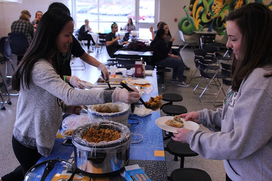 Junior Kate Miller gives junior Sydney Ralston jambalaya at Mardi Gras on Friday, Feb. 24.