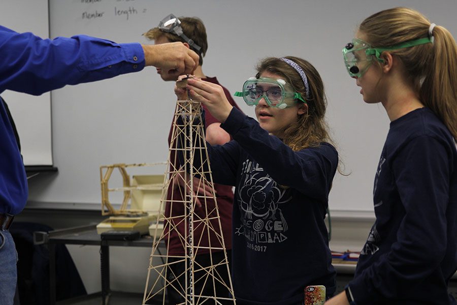 Freshman Eva Burke helps a judge secure a bucket to her tower during the towers competition. 