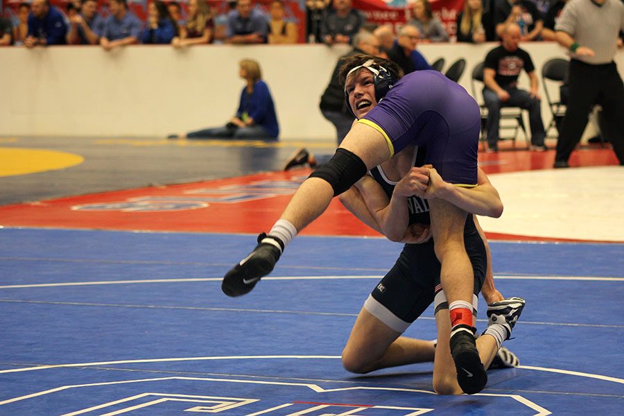 Focusing on his match, senior Joey Gray flips his opponent. 