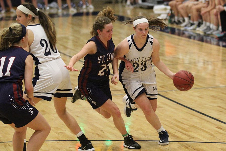 Advancing towards the basket, sophomore Claire Kaifes dribbles the ball, arm and arm with a defender.