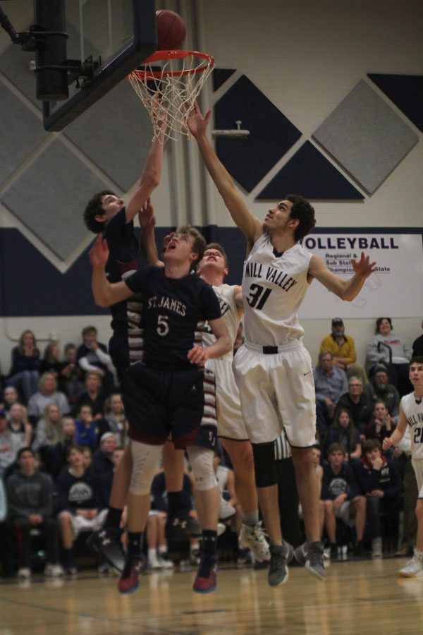 While the St. James offense goes up to score, senior Darius McLemore jumps up to rebound the ball.