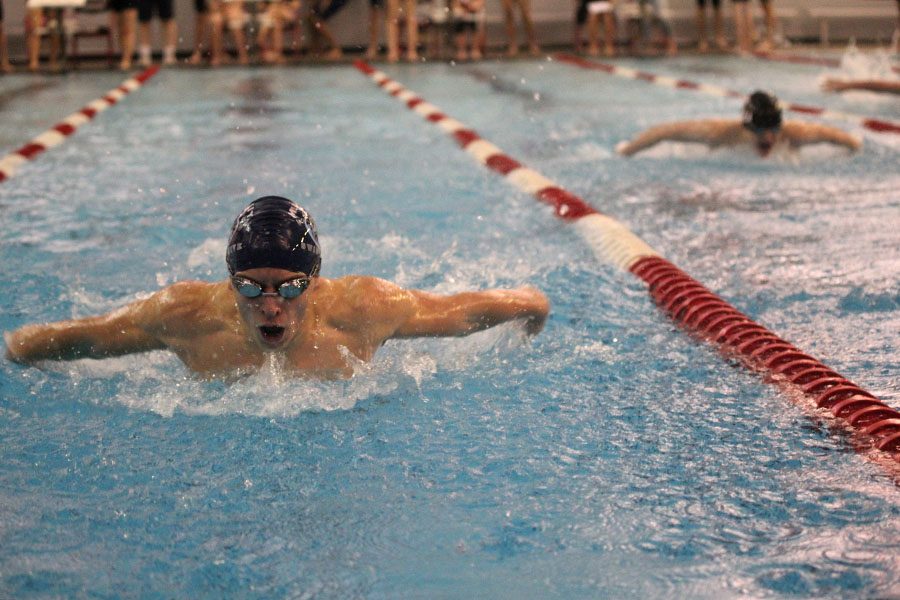 Lifting himself out of the water, sophomore Carter Lawson competes in the 100 butterfly at Lansing on Tuesday, Jan. 31.